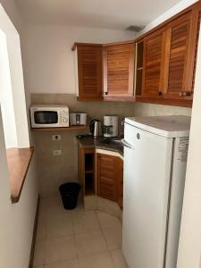 埃斯特角城Hotel Club de La Barra的小厨房配有白色冰箱和木制橱柜。