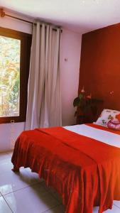 瓜拉米兰加Pousada Raízes Guaramiranga的一间卧室设有红色的床和窗户。