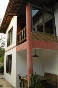 瓜拉米兰加Pousada Raízes Guaramiranga的带阳台和桌椅的房子