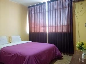 万卡约CasaHotel Centro - Huancayo的一间卧室设有紫色的床和大窗户