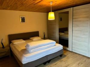 GouvyLovely holiday home in Gouvy with sauna的一间卧室配有一张带白色床单和镜子的床