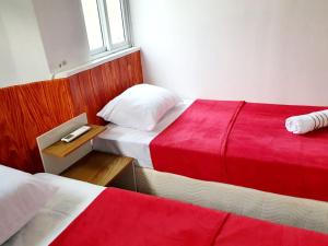 里约热内卢Matianellu Hostel的一间卧室配有两张红色和白色床单