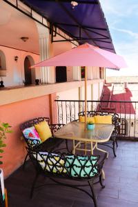 莱昂洛斯巴尔肯斯莱昂酒店的阳台配有一张桌子和椅子,配有粉红色的雨伞