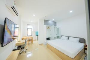 胡志明市Chanh Huy Apartments & Hotel的一间卧室配有一张床、一台电视和一张书桌