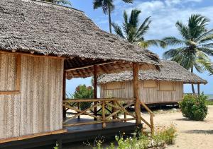 MkwajaBarry's Beach Resort的海滩上茅草屋顶的小屋