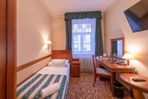 布拉格Hotel Meteor Plaza Prague的配有一张床、一张书桌和一扇窗户的酒店客房