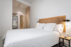 塞维利亚Magno Apartments San Gil - Shared Jacuzzi的卧室配有一张白色大床和木制床头板