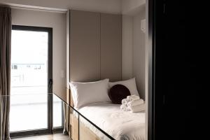 雅典The Rooster's Egg的一间卧室配有一张带白色床单的床和一扇窗户。