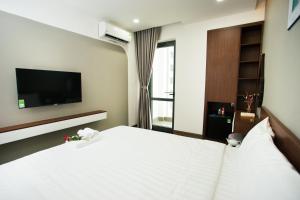芽庄Tesoro Hotel的卧室配有白色的床和电视