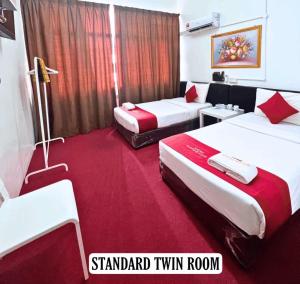 哥打巴鲁ASLAH BOUTIQUE HOTEL的酒店客房,设有两张床,铺有红地毯。