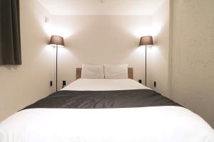 札幌HOTEL WHEAT WACCA的一间卧室配有一张带两盏灯的大型白色床。