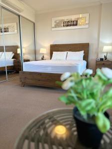 悉尼Best location apartment in Olympic park的一间卧室配有一张床和一张植物桌子