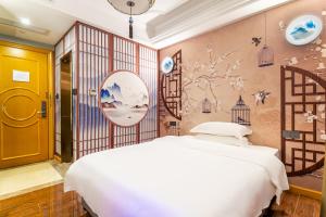 广州拼图酒店（中山八路陈家祠地铁站店）的卧室配有白色的床和鲜花墙