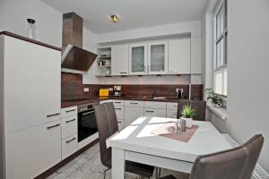 海利根达姆Residenz von Flotow Wohnung 13的厨房配有白色橱柜和桌椅
