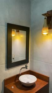 伊卡普伊Lyttos Bungalows的浴室设有水槽、镜子和灯