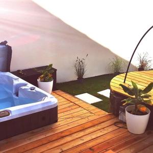 南特Ô'date gîte &spa的木甲板上的热水浴池,种植了盆栽植物