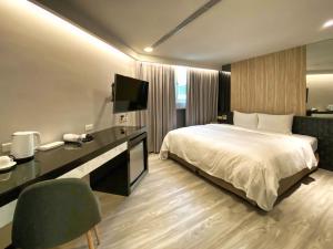 台北旅居文旅-西门驿站的酒店客房配有一张床和一张书桌及一台电视