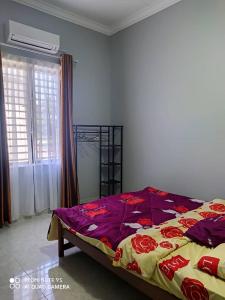 哥打巴鲁The Family Guesthouse的一间卧室配有一张带紫色和黄色毯子的床