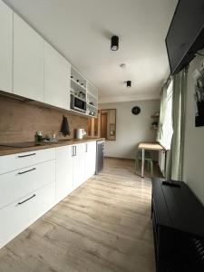 叶卡布皮尔斯Apartamenti Jēkabpilī的厨房铺有木地板,配有白色橱柜。