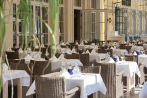鲁斯特钟岩欧洲主题公园&冒险度假村四星级高级酒店的餐厅设有白色的桌子和藤椅