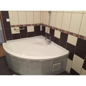 福纽德福纽德巴拉顿湖旅馆的浴室铺有棕色和白色瓷砖,配有浴缸。