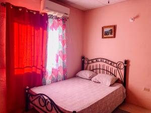 西班牙港Apartment at Trincity Central Road的一间卧室配有一张带红色窗帘的床和窗户