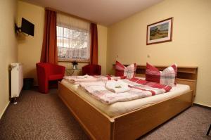 施特拉尔松德Hotel am Stadtwald的一间卧室配有一张带红色枕头的大床