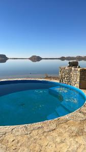 锡瓦Siwa Relax Retreat Ecolodge的靠近水体的大型蓝色游泳池