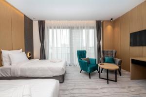 巴统The Grandeur Hotel的酒店客房带两张床和一张桌子以及椅子。