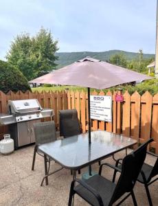 Saint-Férréol-les-NeigesLoft LèSKImo, lit king, sauna, piscine et montagne的桌椅、雨伞和烧烤架