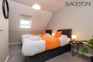 达灵顿Champagne House - 4 Bed Property plus 2 sofa beds by BPNE的小客房内的两张床,配有橙色枕头