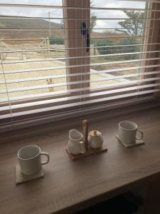 多尼戈尔Dolmen Lodge.的窗边桌子上放两个杯子和碟子
