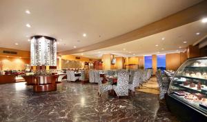 沙马林达ASTON Samarinda Hotel and Convention Center的一间带桌椅和吊灯的餐厅