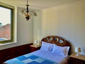 波瓦-迪瓦尔津Povoa Center Beach Apartment的一间卧室设有一张床、一个窗户和一个吊灯。