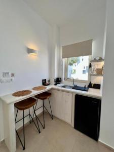 皮尔戈斯Thealos Santorini ( close to square)的厨房配有水槽和2个吧台凳