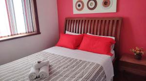 特雷索波利斯Pousada Jupter的一间卧室配有红色枕头,另一张床配有2条毛巾
