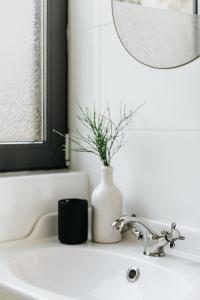 泽拜盖尼Hegyi Pihenő的浴室水槽设有白色花瓶和镜子