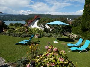 沃尔特湖畔韦尔登Ferienwohnung Schellander Privatstrand的草坪上两把蓝色椅子和一把伞