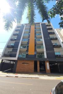伊瓜苏Novo central 2 quartos wifi/garagem/elevador的一座高大的建筑,前面有一棵棕榈树