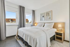 登茨林根Empire Living: Denzlingen Marktplatz的卧室设有一张白色大床和两个窗户。