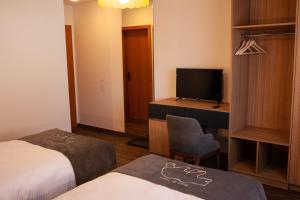 Courroux德乐奥酒店的酒店客房设有两张床、一张桌子和一台电视。