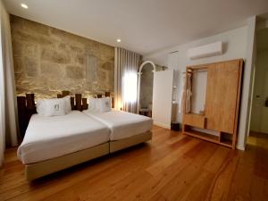 波尔图Porta Nobre - Exclusive Living Hotel的一间卧室设有一张大床和石墙