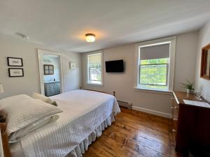 WaitsfieldThe Griff Inn的卧室配有白色的床和2扇窗户。