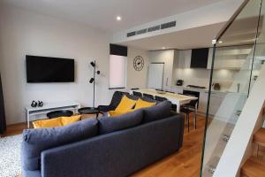 墨尔本Flagstaff Hill West Melbourne的客厅配有蓝色的沙发和黄色的枕头。