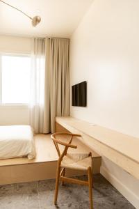 Havre-AubertPetit hôtel de la Montagne的一间卧室配有书桌、一张床和一把椅子
