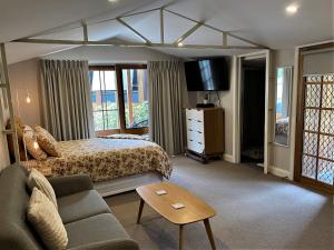 波塔灵顿The Cosy Bungalow的一间卧室配有一张床、一张沙发和一台电视。