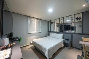 仁川市Alps Motel的一间卧室配有一张床、一张书桌和一个窗户。