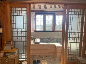 求礼郡Hanok Stay - JukRokJungSa的一间带浴缸的浴室,位于带窗户的客房内