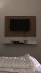 井里汶Damai Guest House Cirebon的床上墙上的电视机