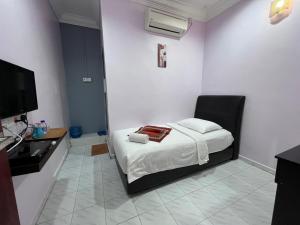 克提HOTEL RAUDHAH Kerteh的一间卧室配有一张床和一台电视
